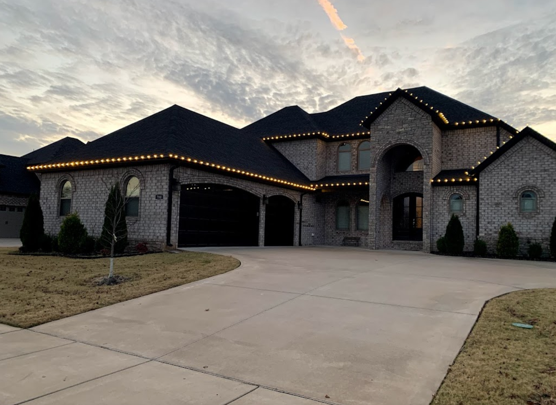 A large brick house with christmas lights on the roof