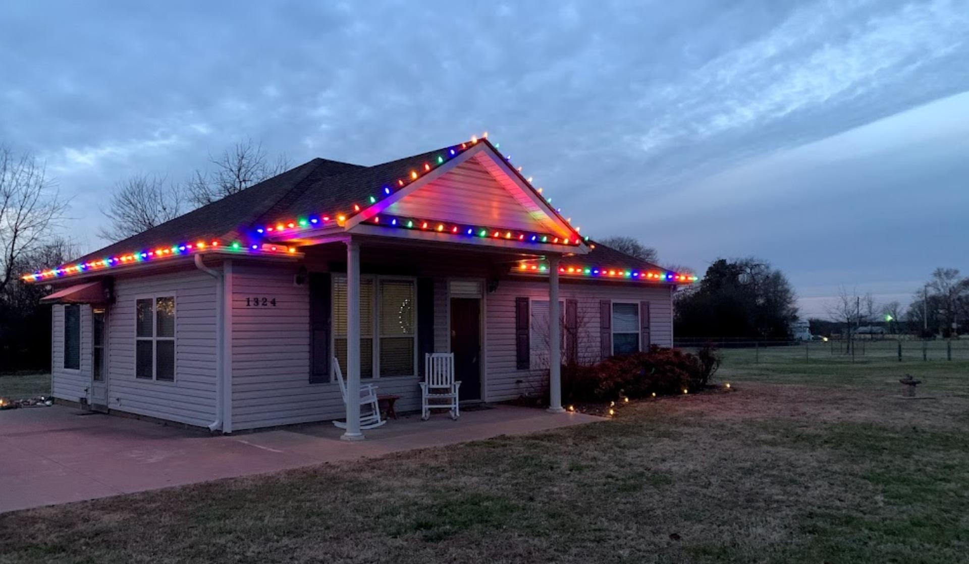 A house with christmas lights on the porch and roof.