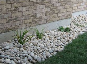 A garden with rocks and plants in front of a brick wall