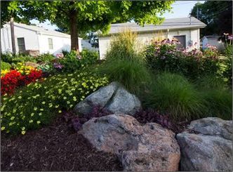 A garden with rocks and flowers in front of a house.