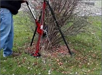 A man is standing next to a red object in the grass.