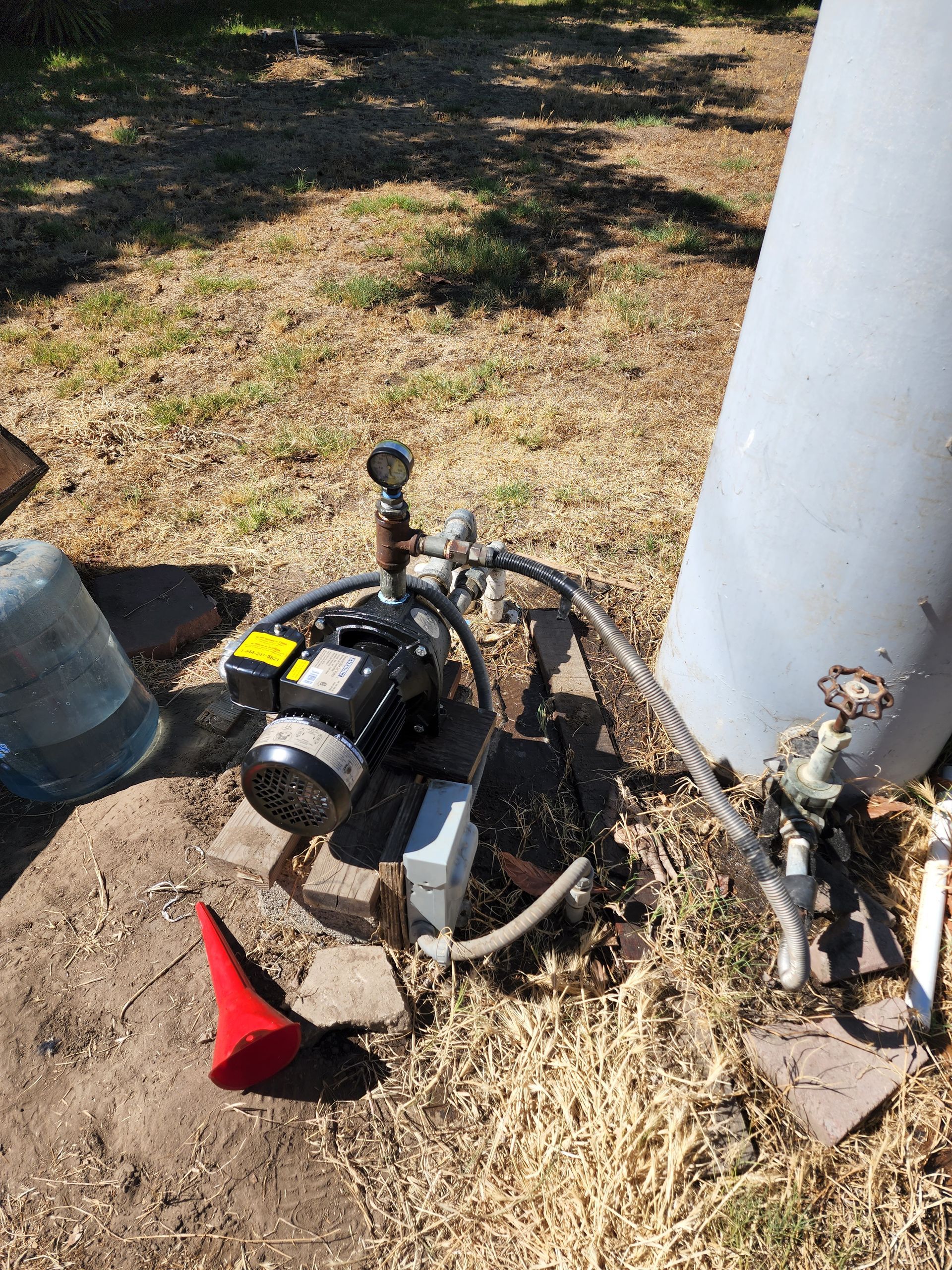 A red cone is laying on the ground next to a water heater