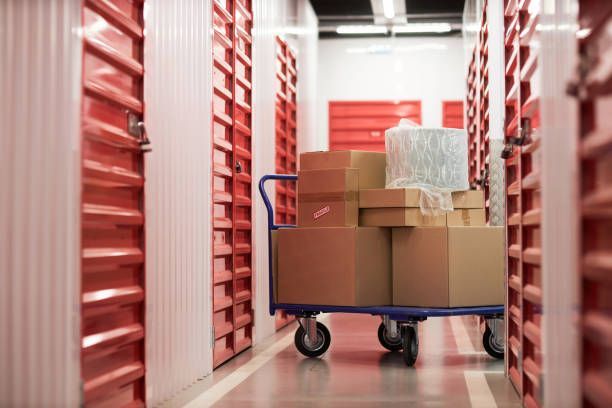 A cart with cardboard boxes on it in a corridor of a storage.