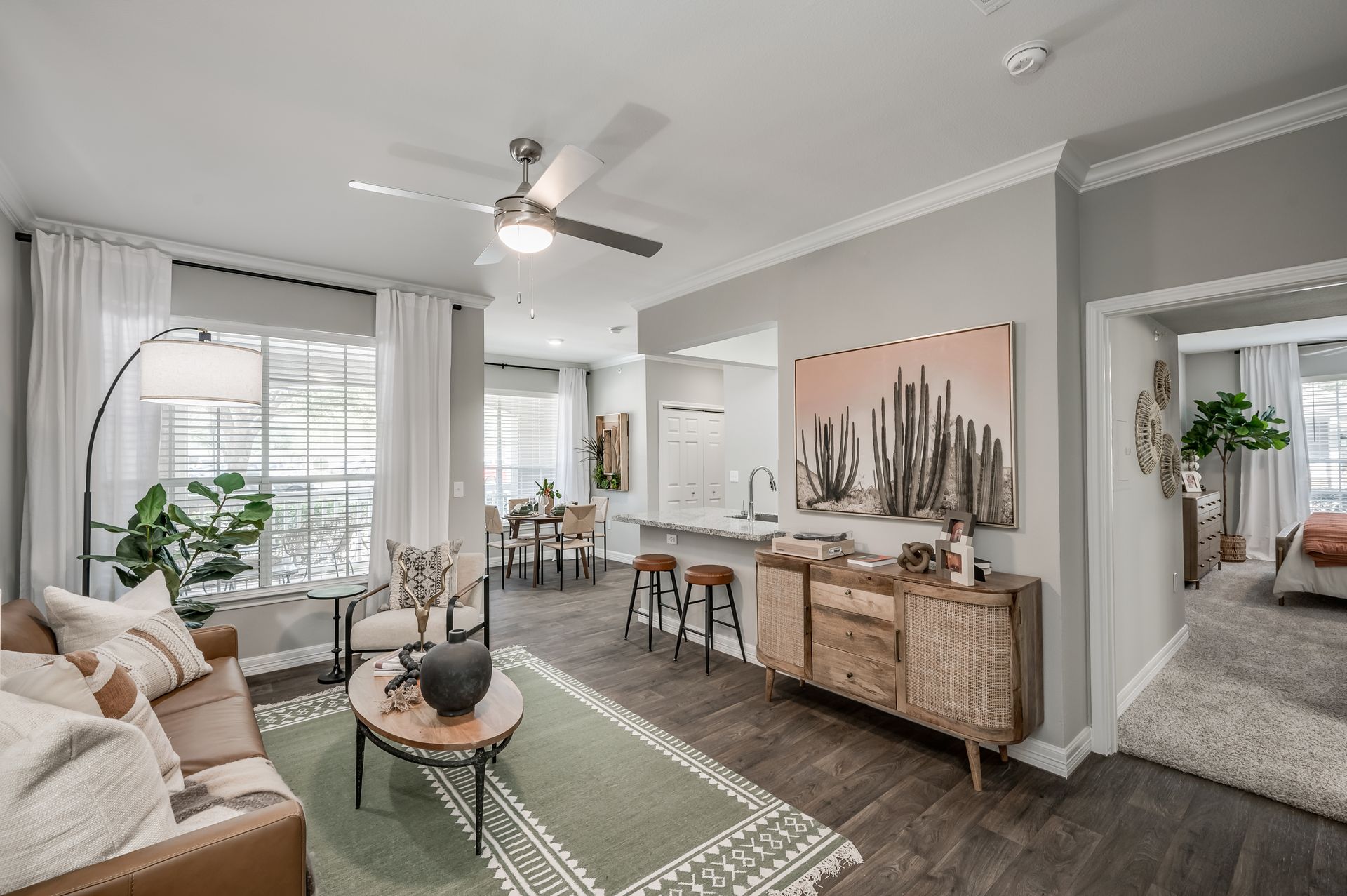 A living room with a couch , table , chairs and a ceiling fan.