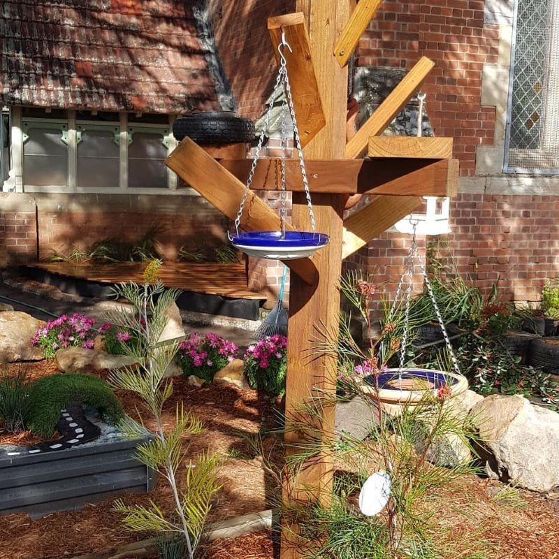 A Bird Feeder is Hanging From a Wooden Post in a Garden — Garden Vogue in Charlestown, NSW
