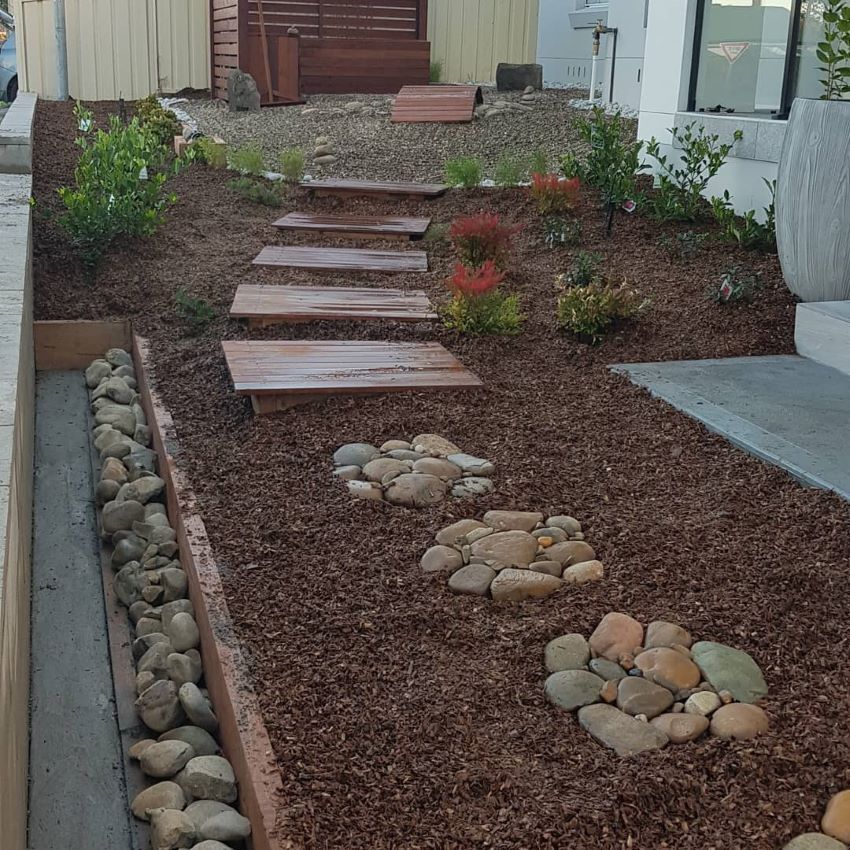 A Wooden Walkway Surrounded by Rocks and Mulch — Garden Vogue in Charlestown, NSW