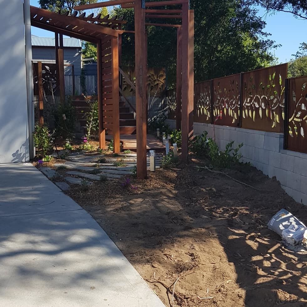 A Wooden Pergola With a Metal Fence Behind It — Garden Vogue in Lake Macquarie, NSW