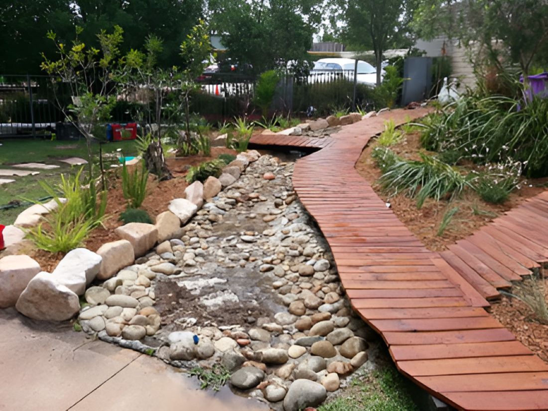 A Wooden Walkway Leading to a Stream in a Garden — Garden Vogue in Charlestown, NSW