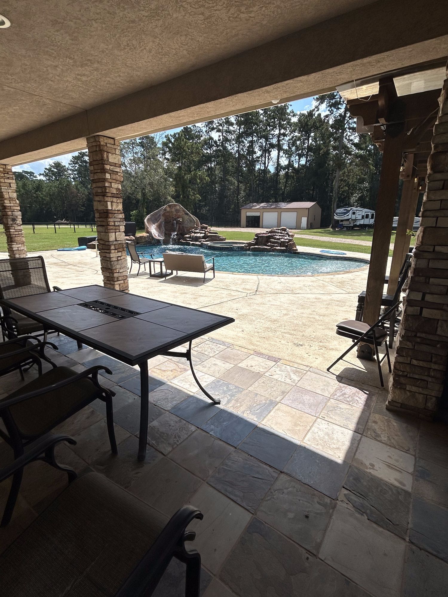 A patio with a table and chairs and a pool in the background.
