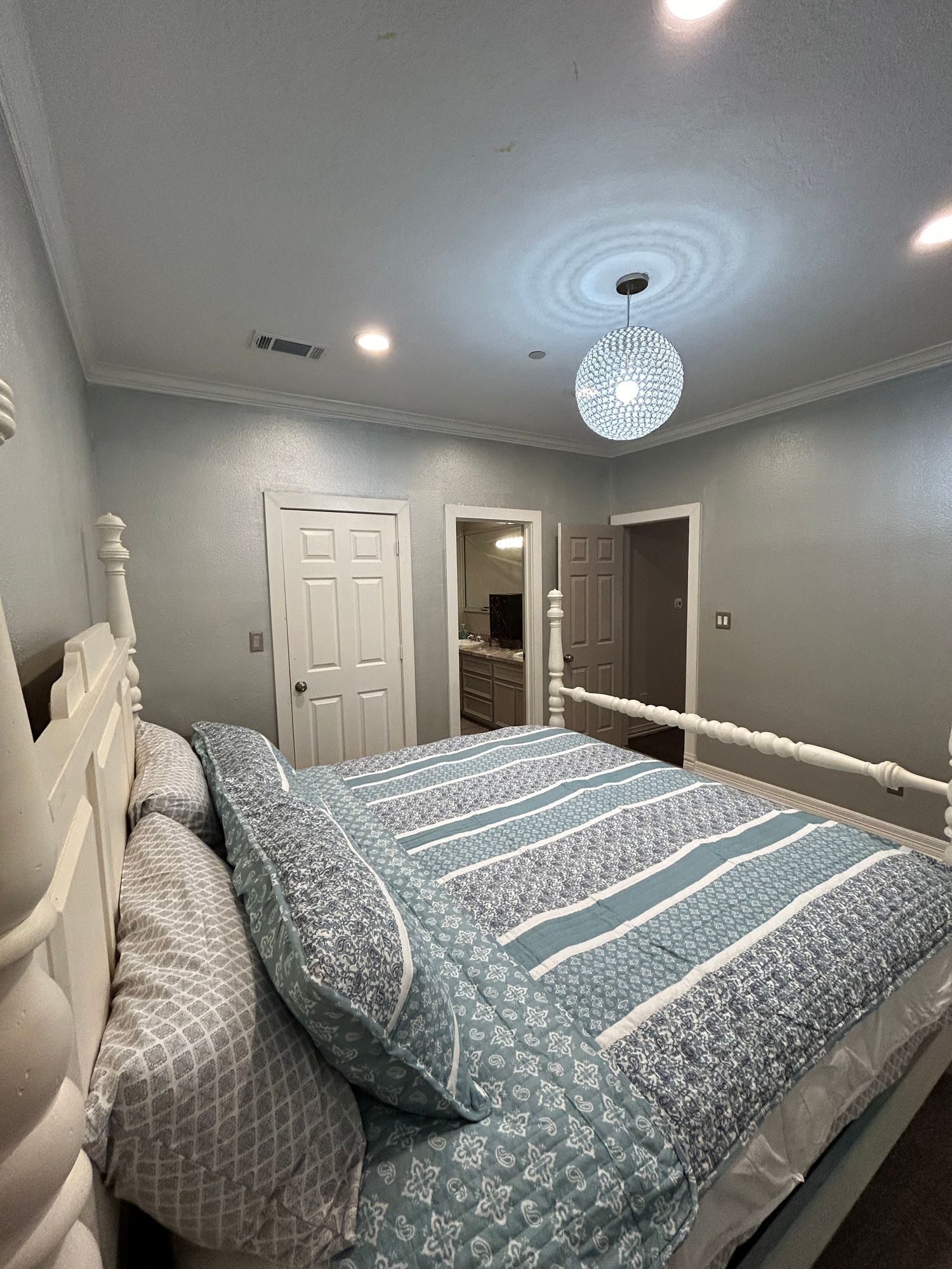 A bedroom with a king size bed and a chandelier hanging from the ceiling.