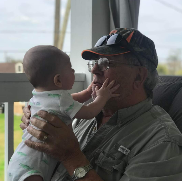 A man is holding a baby in his arms while wearing a watch