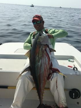 A man is sitting on a boat holding a large fish