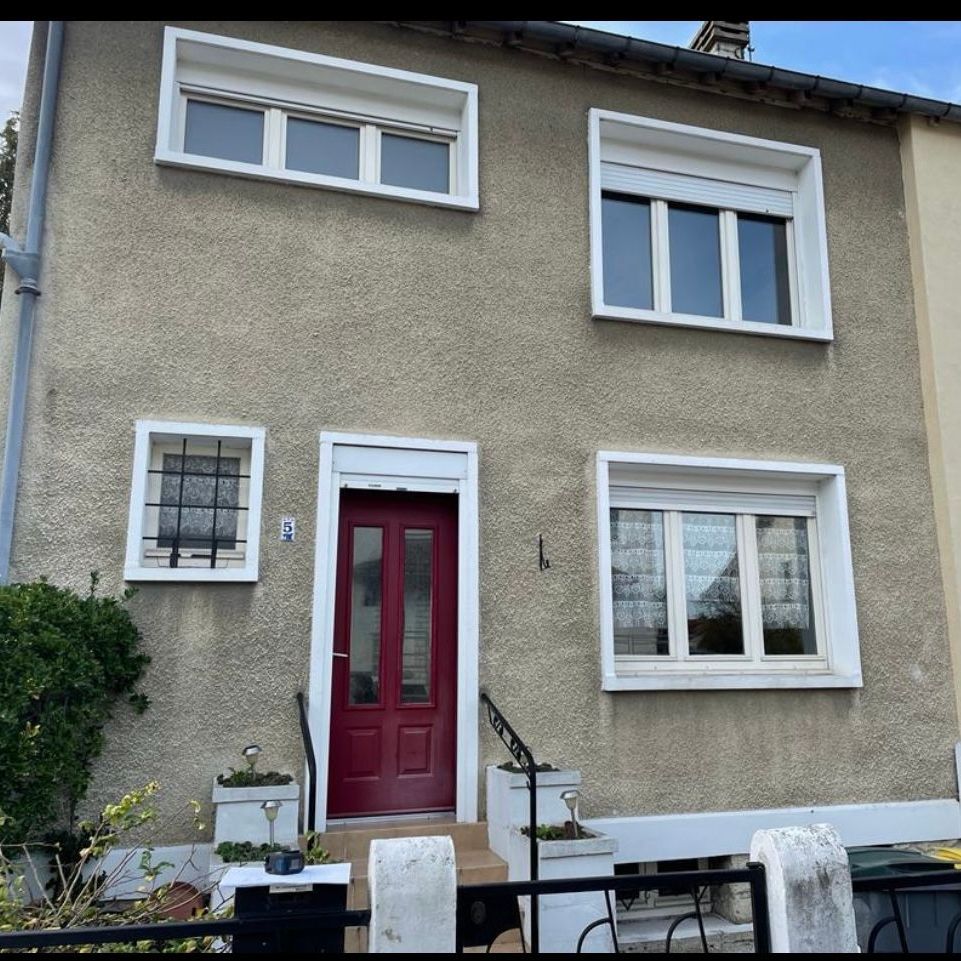 Une maison avec une porte rouge et des fenêtres blanches