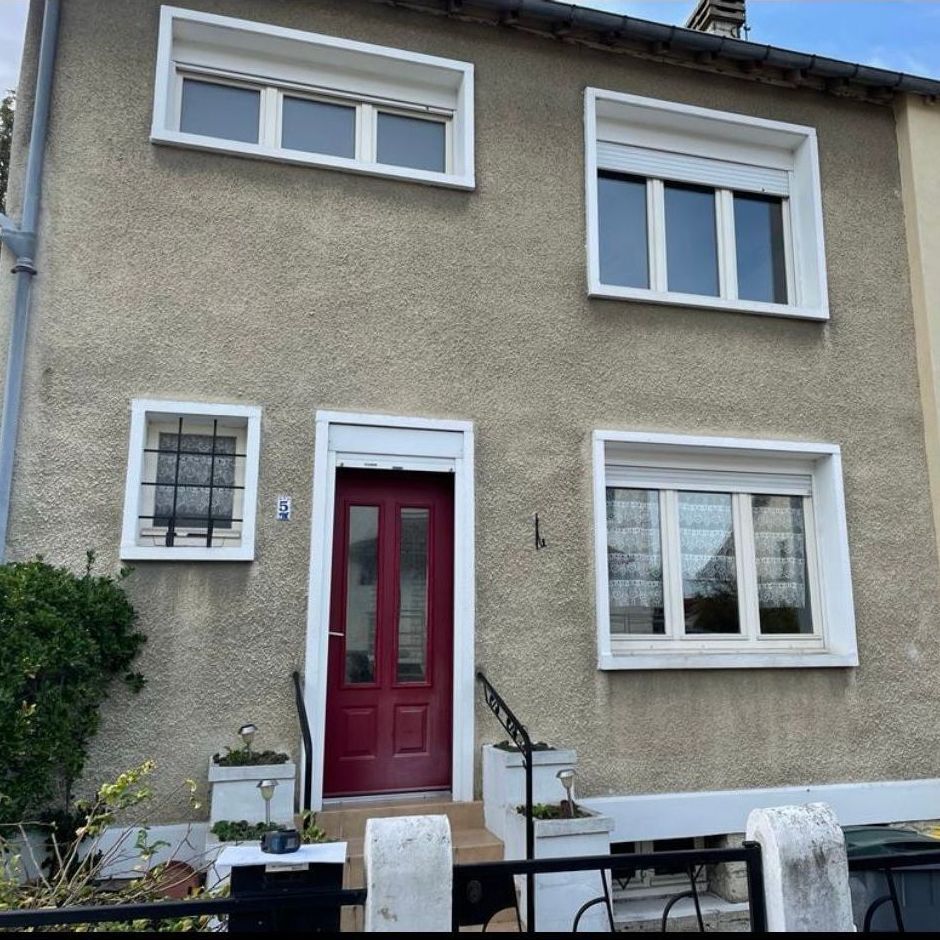 Une maison avec une porte rouge et des fenêtres blanches