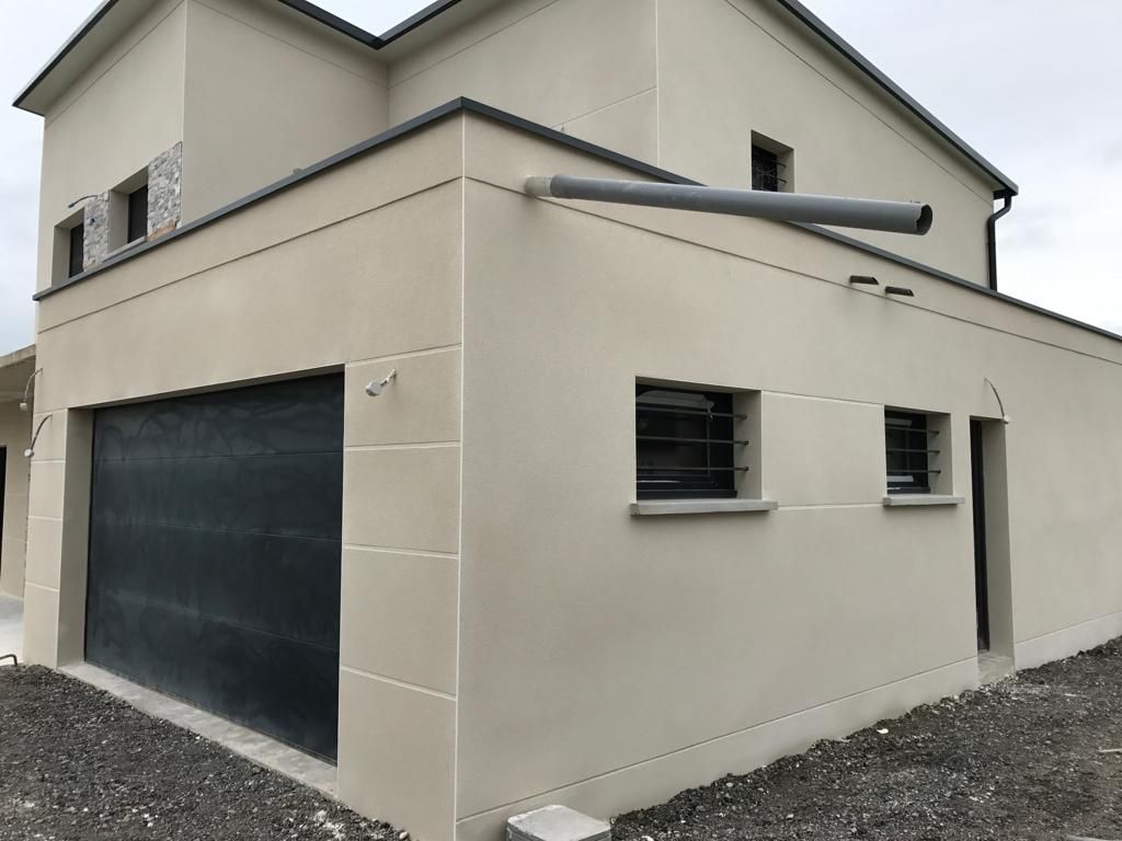 Une grande maison blanche avec une porte de garage noire