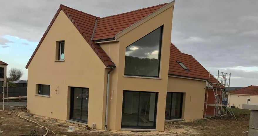 Une maison jaune avec un toit rouge et une grande fenêtre.