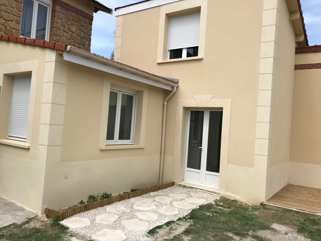 Une maison beige avec une porte et des fenêtres blanches