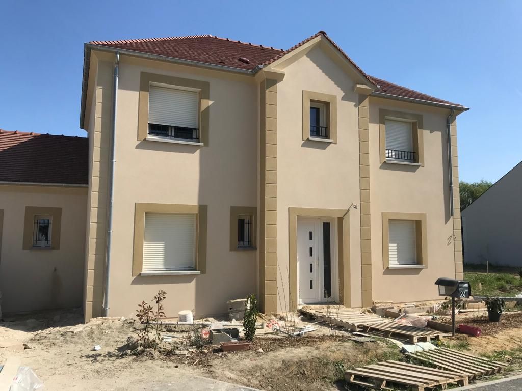 Une grande maison beige avec un toit rouge est en construction.