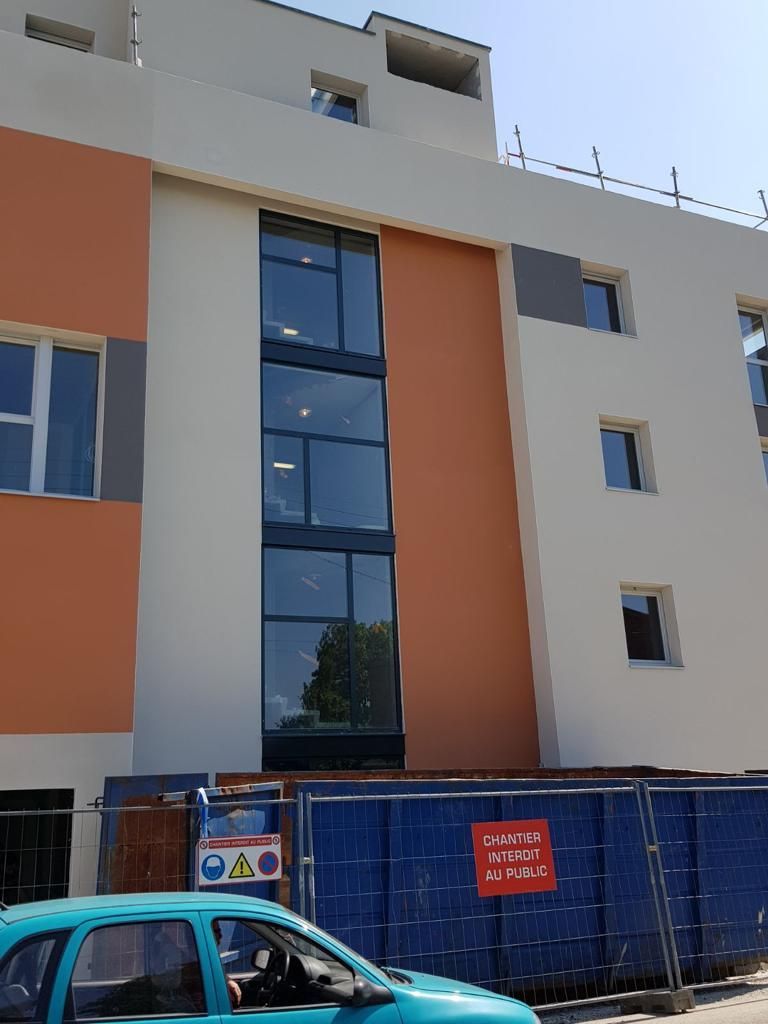 Une voiture bleue est garée devant un bâtiment en construction