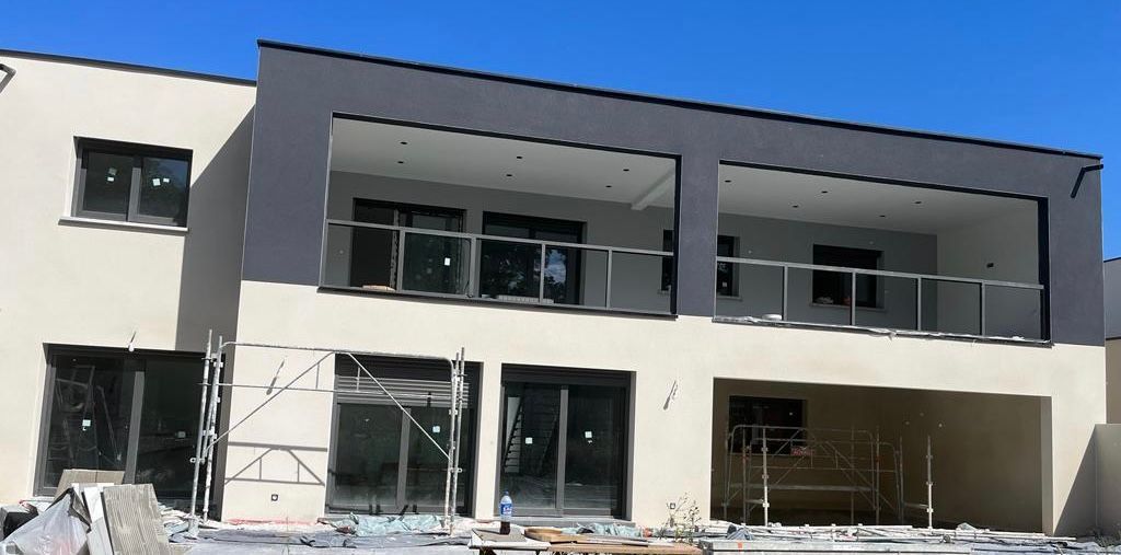 Une grande maison est en construction avec beaucoup de fenêtres et de balcons.