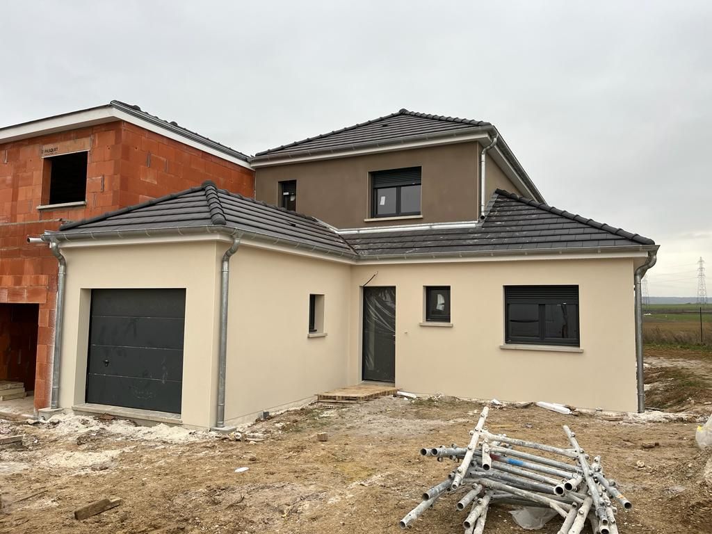 Une maison est en construction dans un champ avec une pile d'échafaudages devant elle.