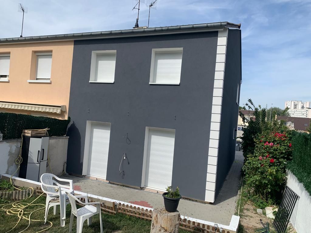 Une maison avec une façade grise et orange est en train d'être peinte.