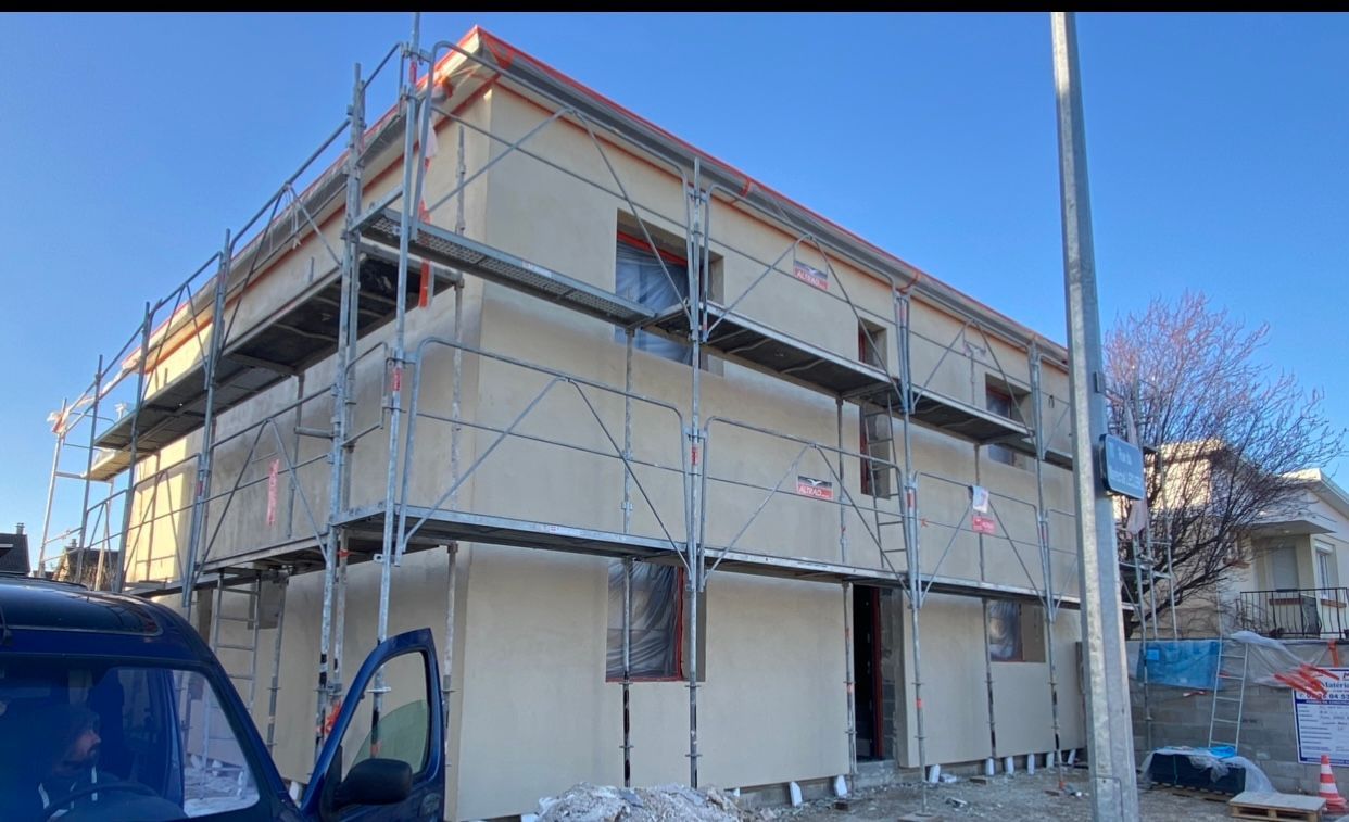 Une camionnette bleue est garée devant un immeuble en construction.