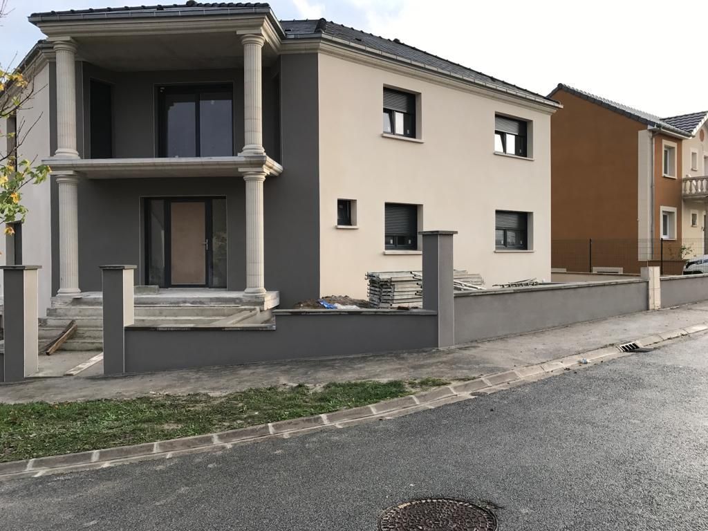 Une grande maison avec une clôture devant elle est en construction.