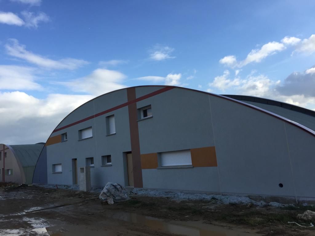 Un grand bâtiment avec un toit incurvé et un ciel bleu en arrière-plan.