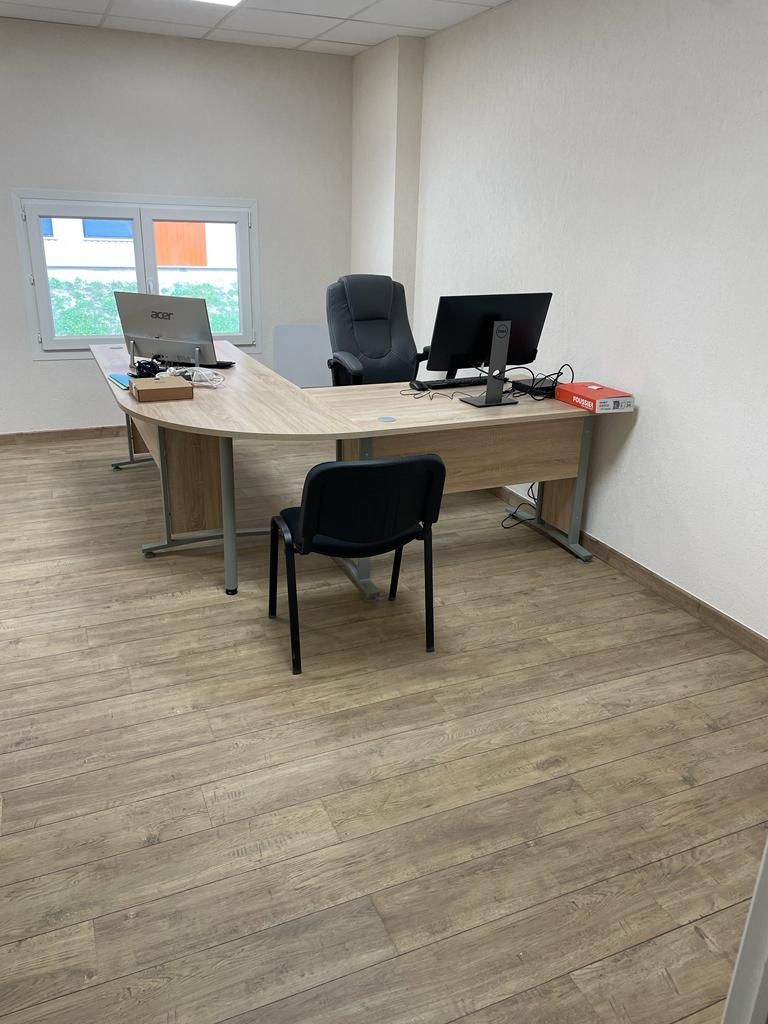 Un petit bureau avec un bureau, une chaise et un ordinateur.