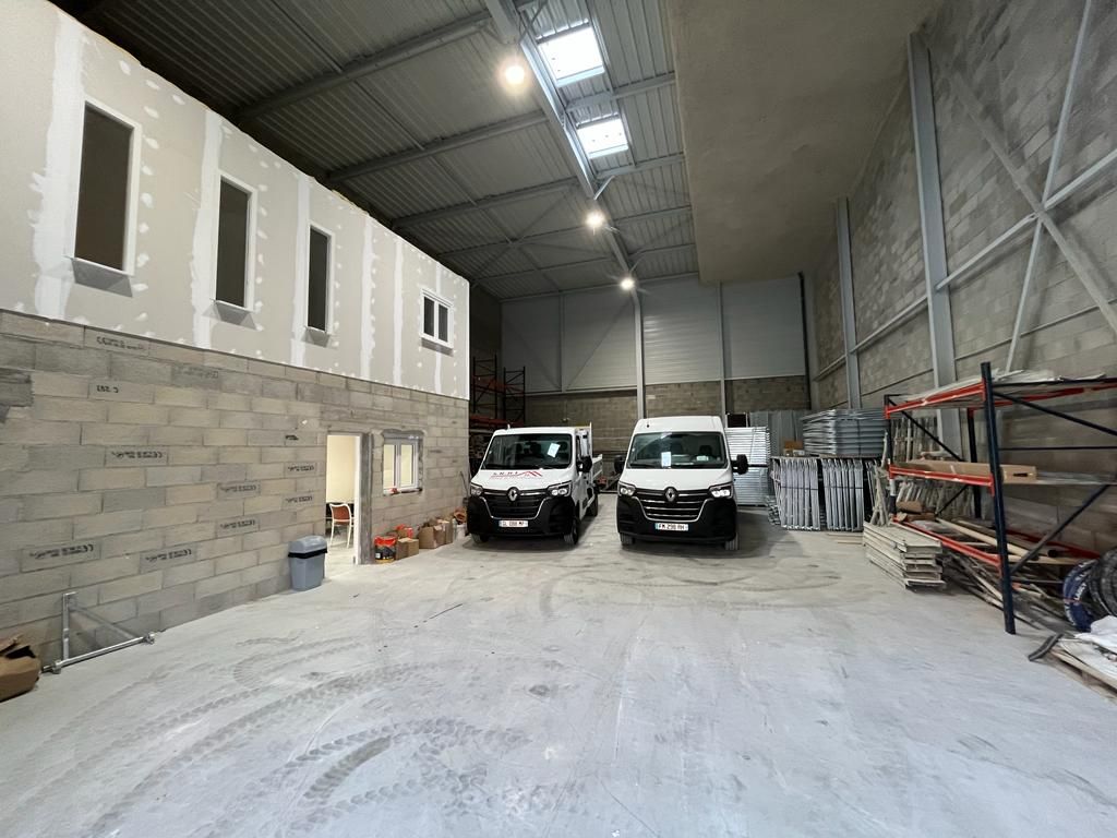 Deux camionnettes blanches sont garées dans un grand entrepôt.