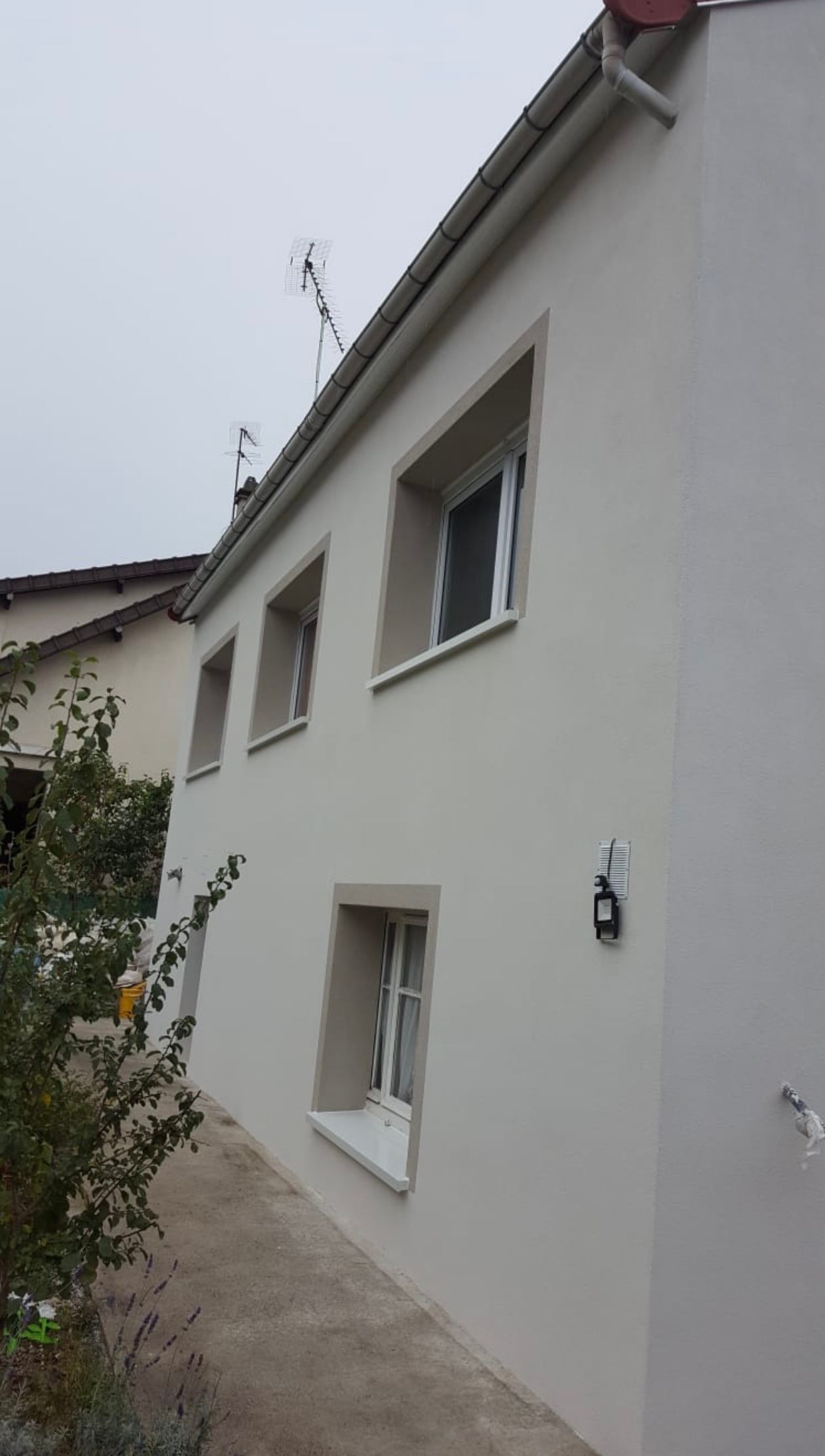 Une maison blanche avec beaucoup de fenêtres sur le côté.