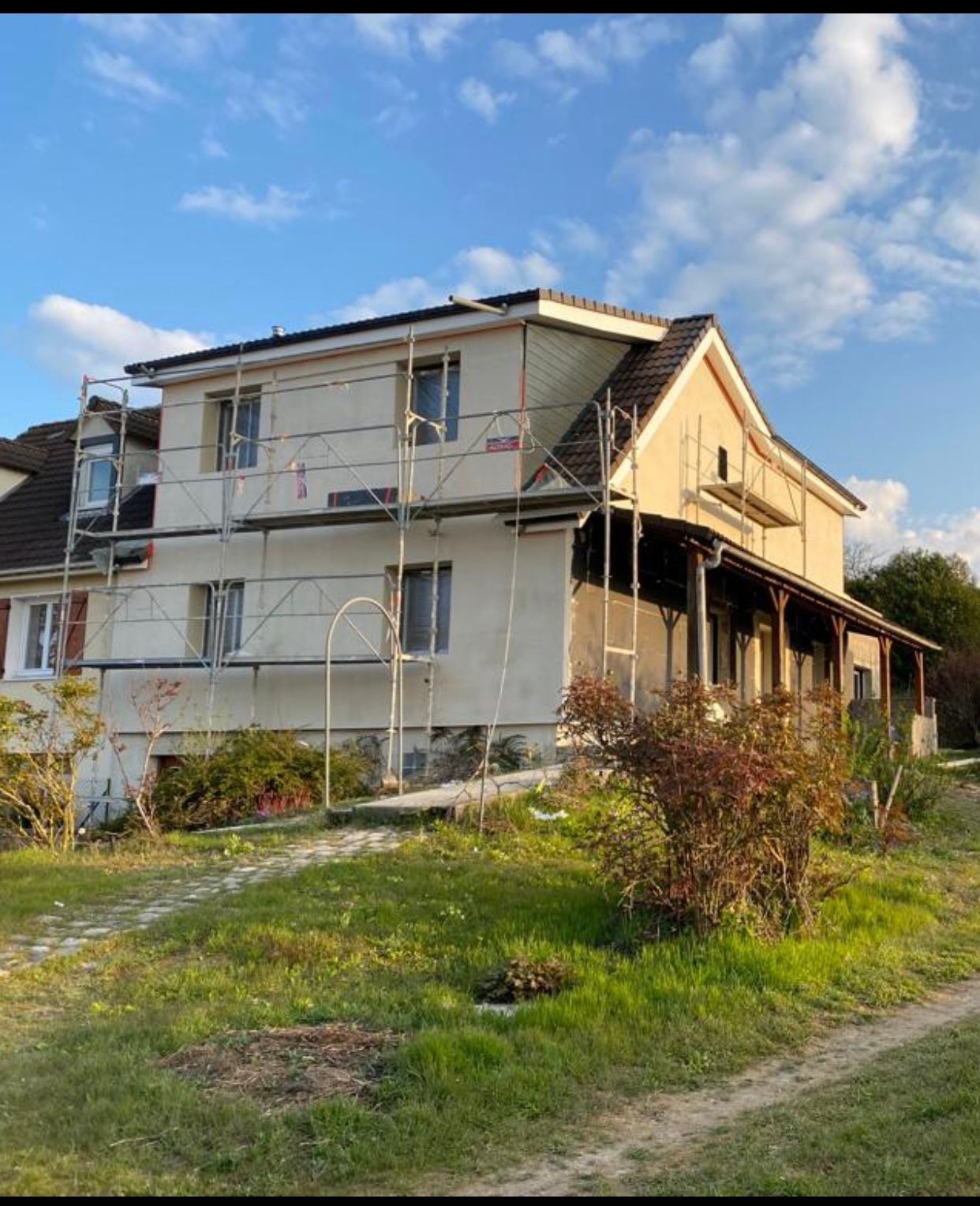 Une maison entourée d'échafaudages est en train d'être peinte.