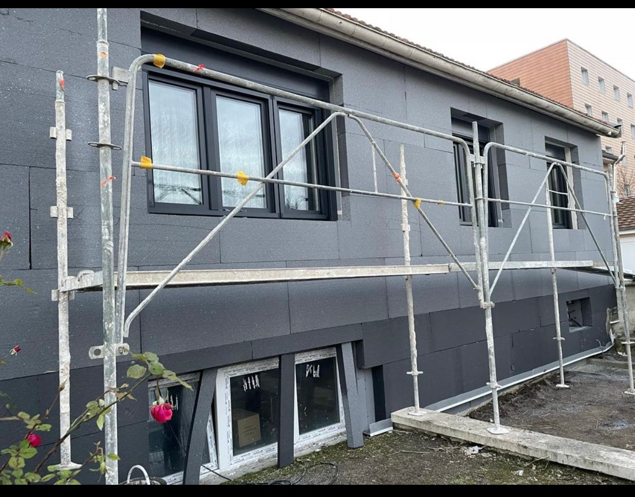 Une maison est en cours de rénovation avec des échafaudages autour.