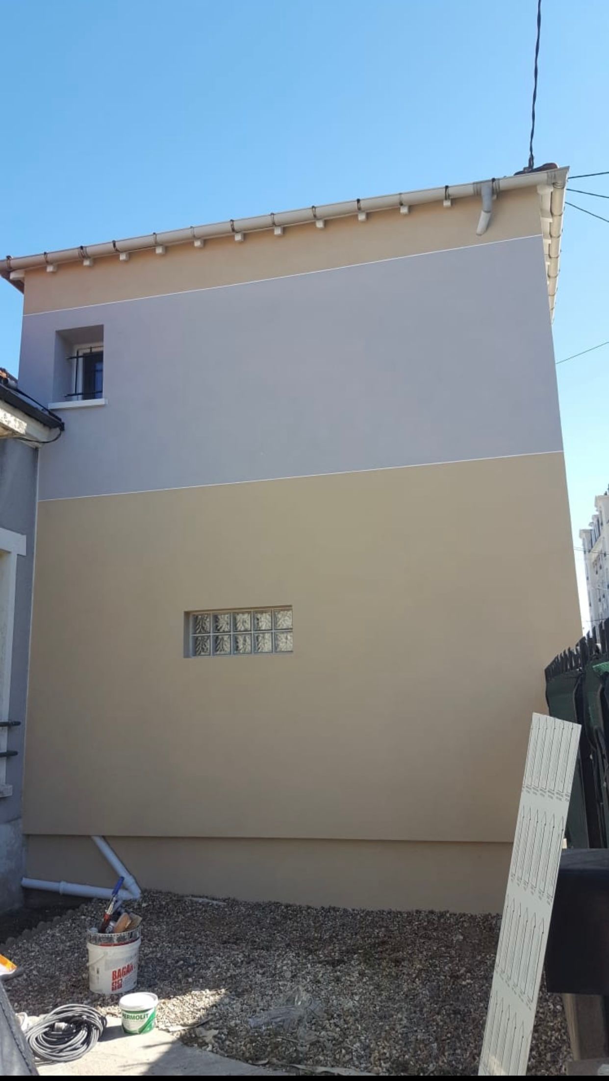 Le côté d'une maison est en train d'être peint.