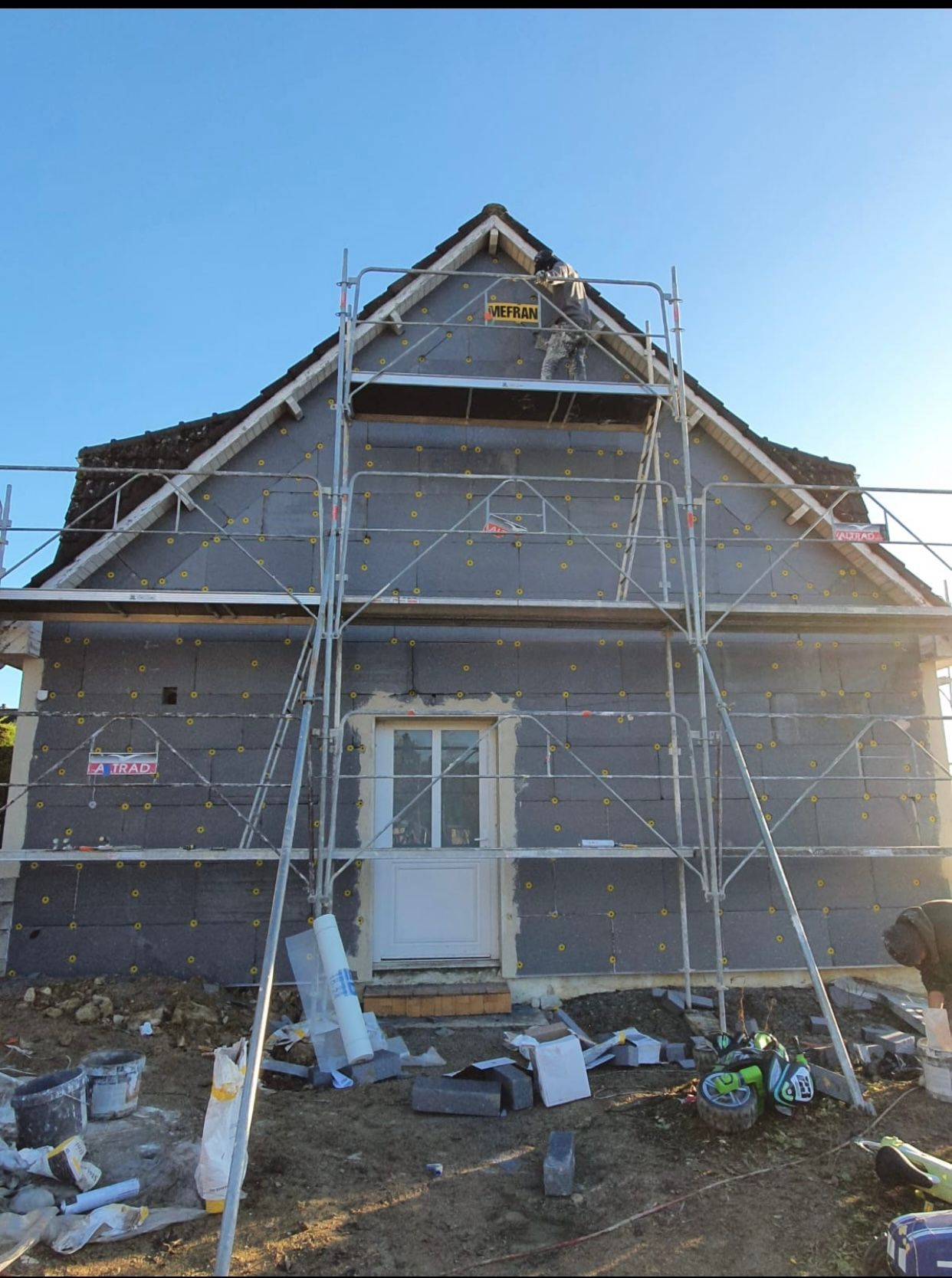 Une maison est en construction avec des échafaudages autour.