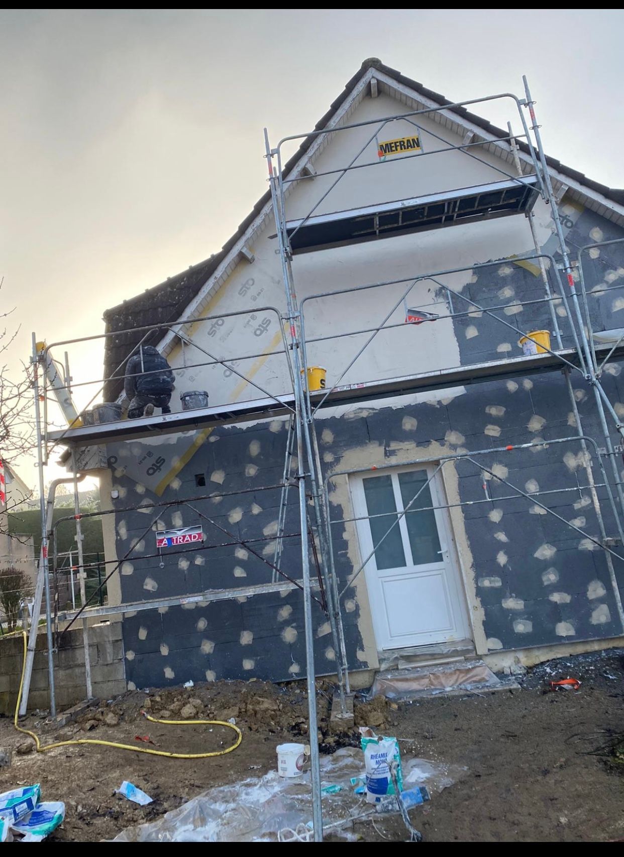 Une maison est en train d'être peinte avec des échafaudages autour.