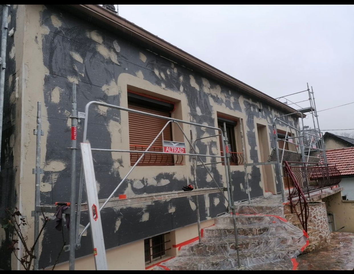 Une maison est en cours de rénovation avec des échafaudages autour.