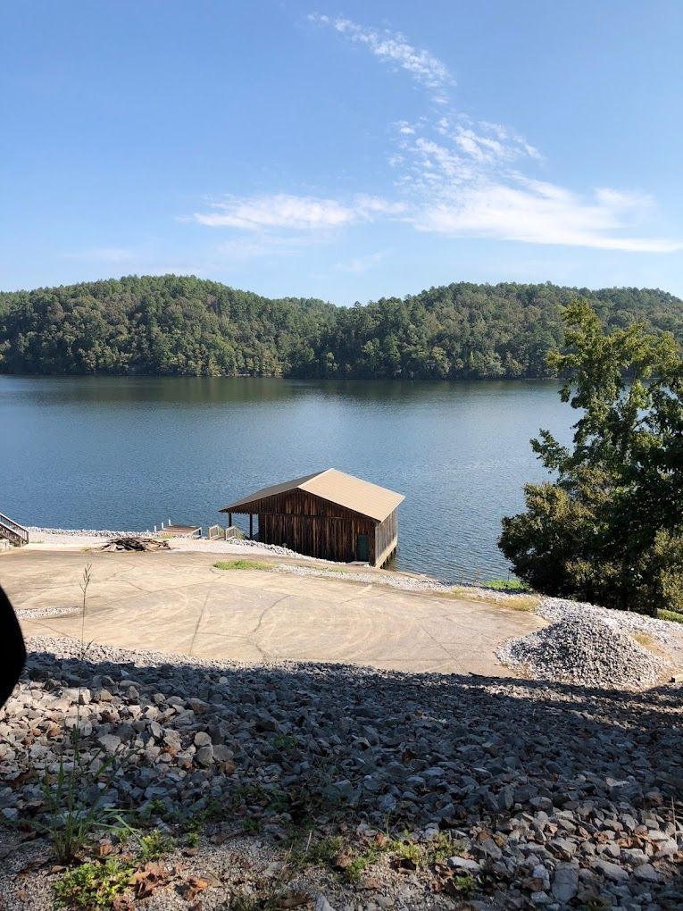 A small house sits on the shore of a lake surrounded by trees.