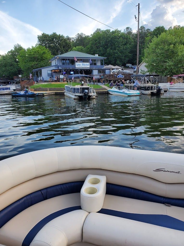 A pontoon boat is floating on a lake with a house in the background