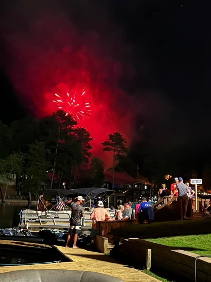 A group of people standing on a dock watching a fireworks display.