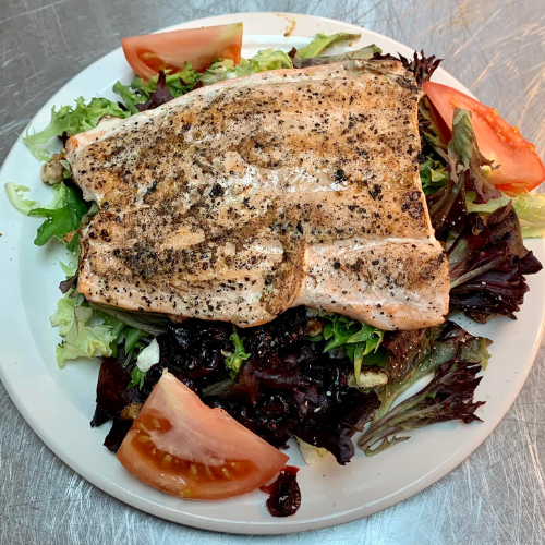 A white plate topped with a piece of meat and vegetables