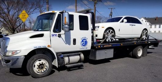 White Rolls-Royce on a flatbed tow truck; blue sky.