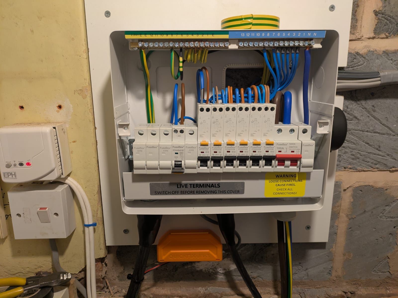 Electrical panel with circuit breakers, wires, and terminals installed on a wall.
