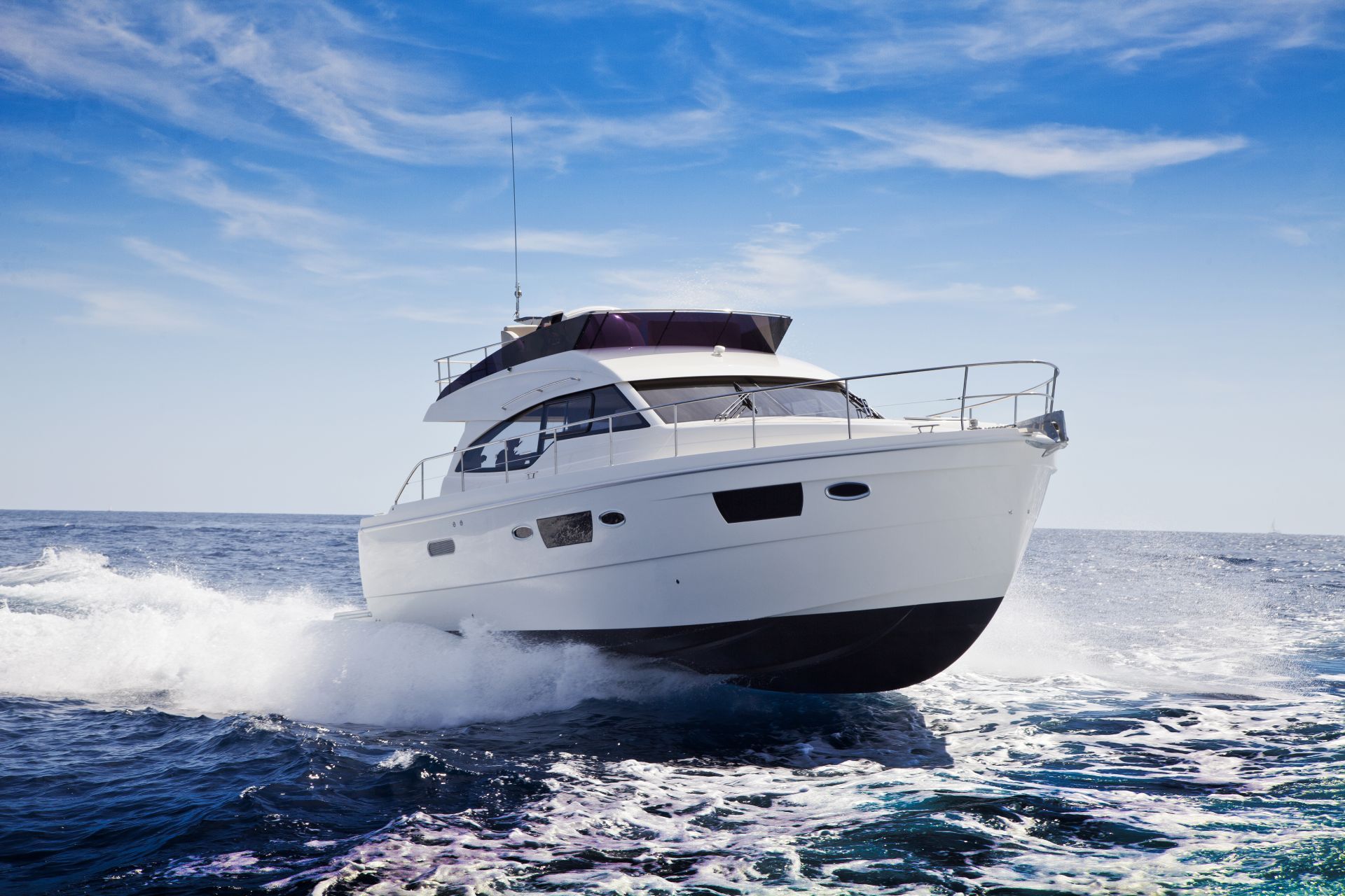White motorboat speeding across blue ocean under a bright sky.