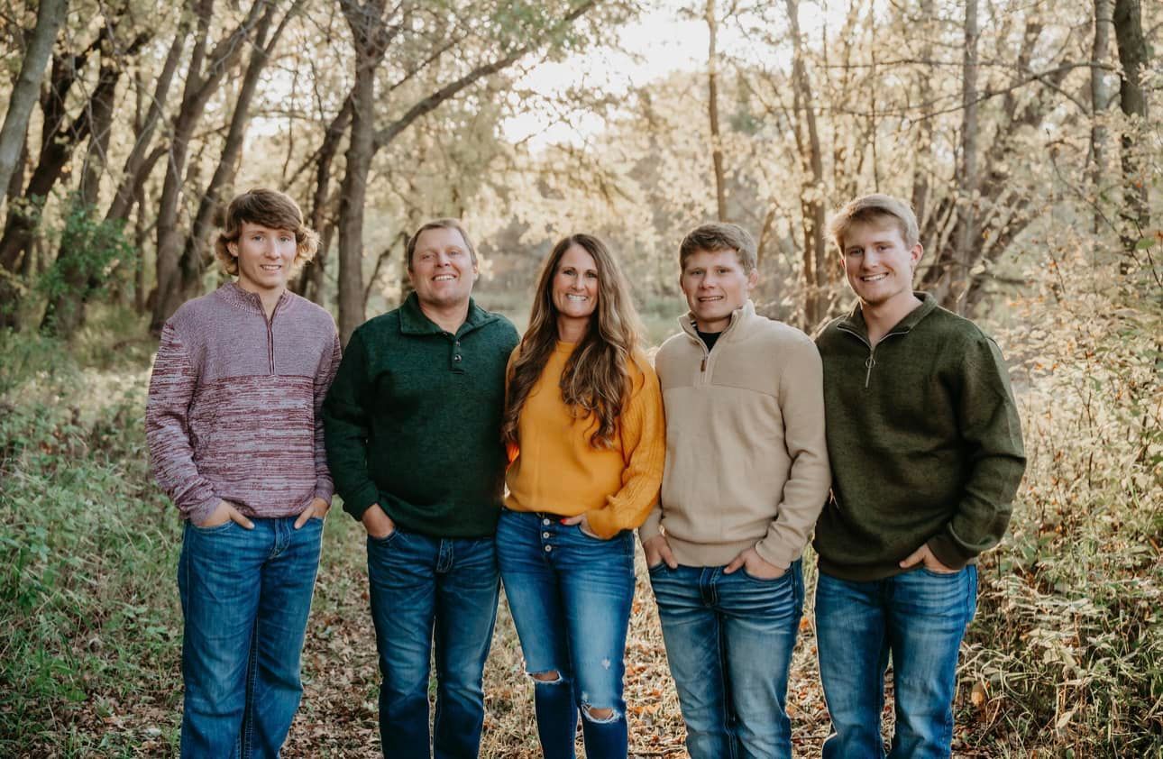 A family is posing for a picture in the woods.