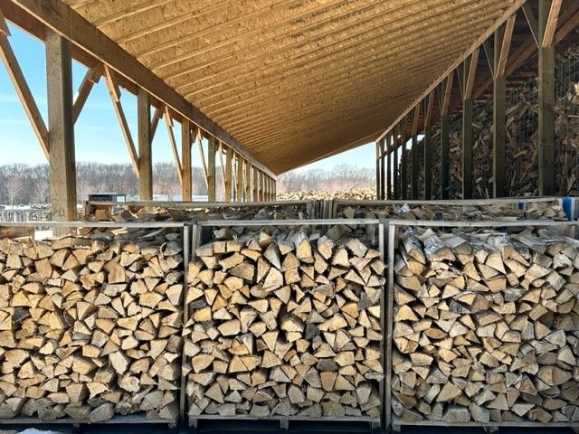 A bunch of logs stacked on top of each other under a roof