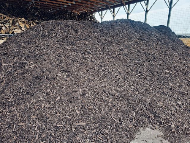 A large pile of wood chips is sitting under a roof.