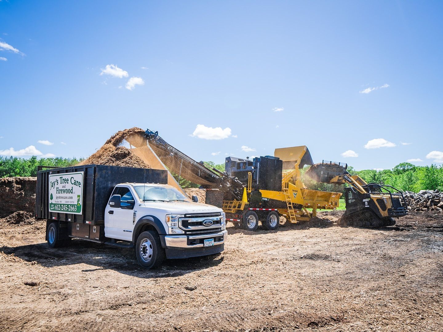 A dump truck is parked in a dirt field next to a bulldozer.