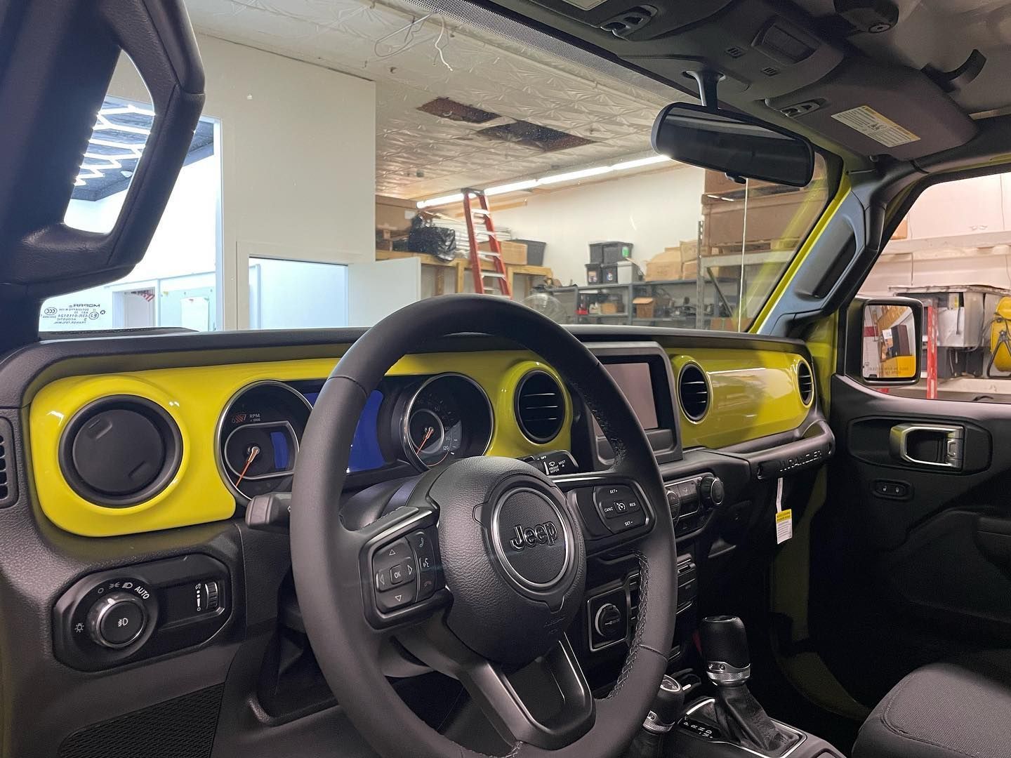 Yellow dashboard and steering wheel inside a car, viewed from the driver’s seat.
